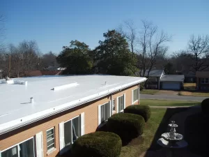A wide-angle view of a white reflective flat roof with multiple vents and a clear blue sky above, highlighting an energy-efficient roofing system.